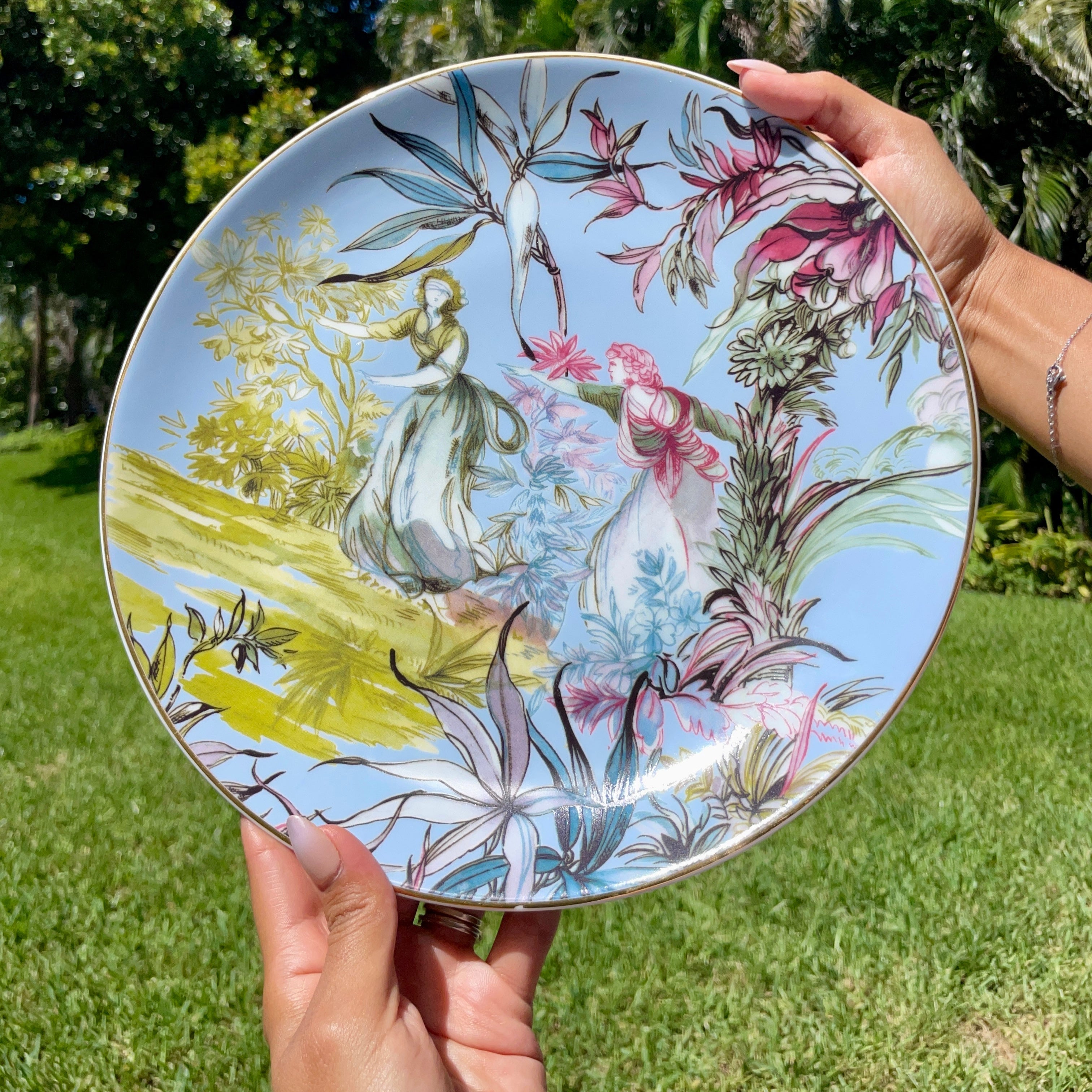Decorative plate with floral and bird design held outdoors