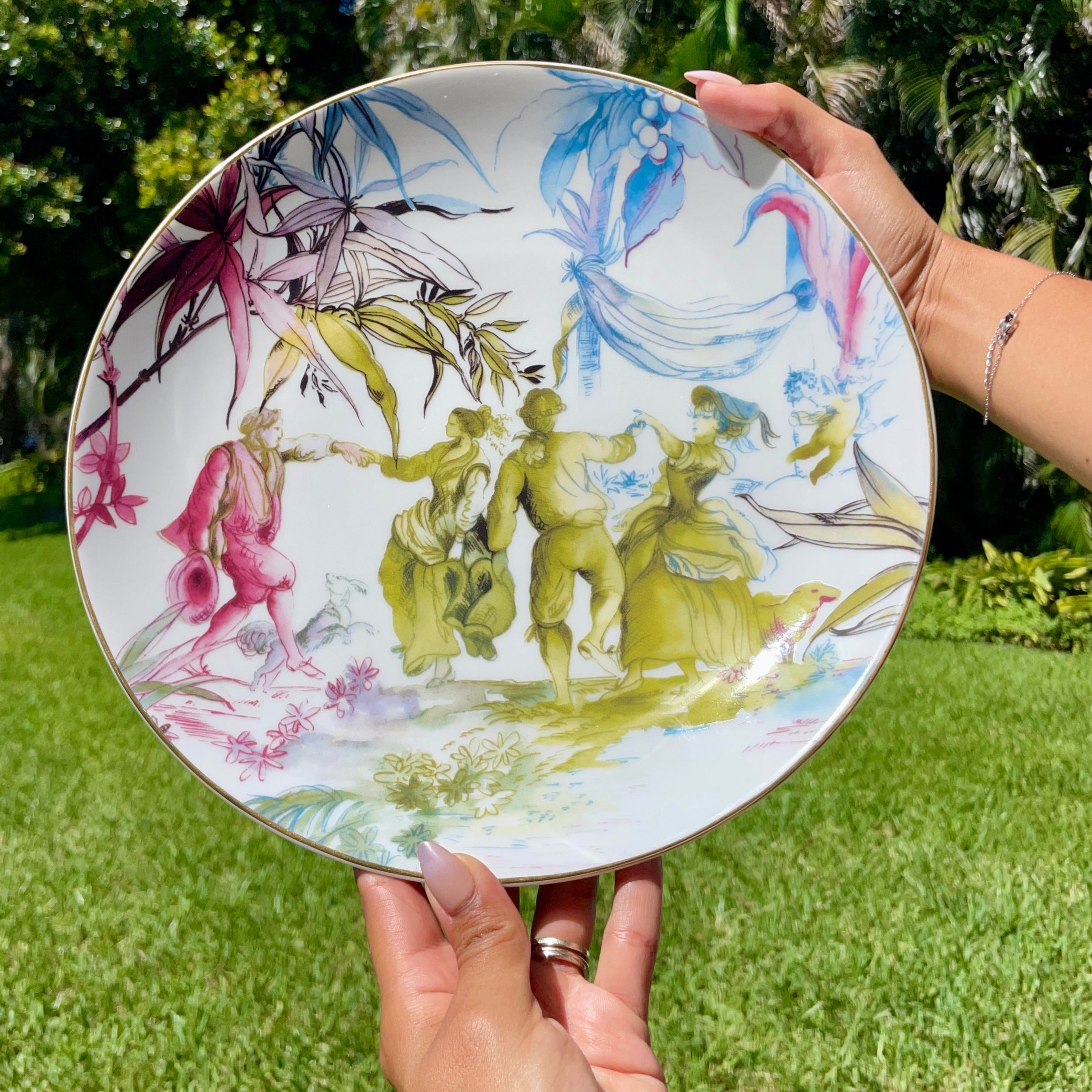 Person holding a decorative plate with artistic design outdoors
